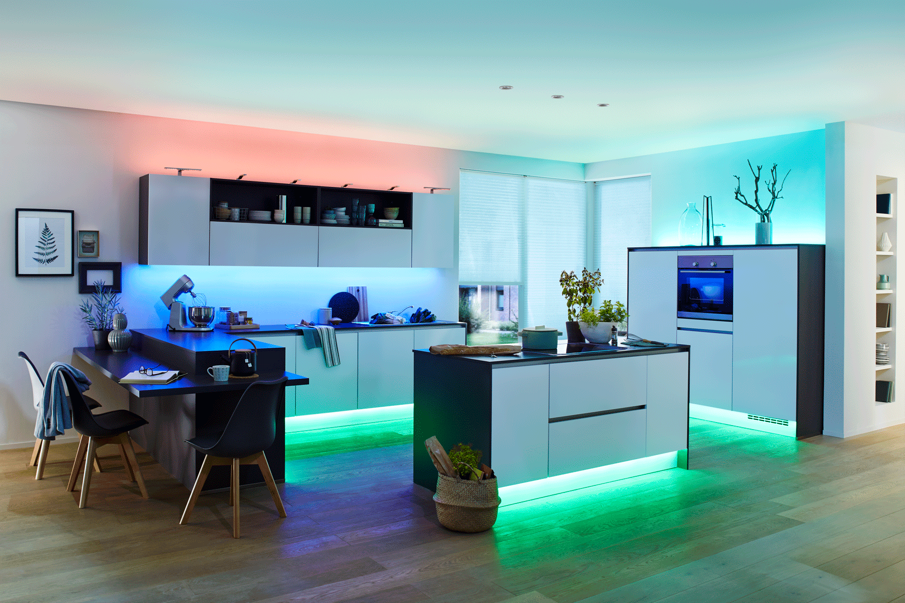 Moderne weiße Kücheninsel und Schränke mit farbiger LED-Beleuchtung und Holzfußboden im Wohnraum