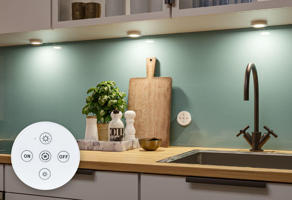 Küchenarbeitsplatte mit Holzbrett, Kräutertopf und modernen LED-Unterbauleuchten mit Fernbedienung.
