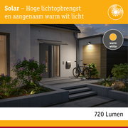 Zonne-energie buitenlamp met warm wit licht aan moderne gevel, energiezuinige LED-verlichting