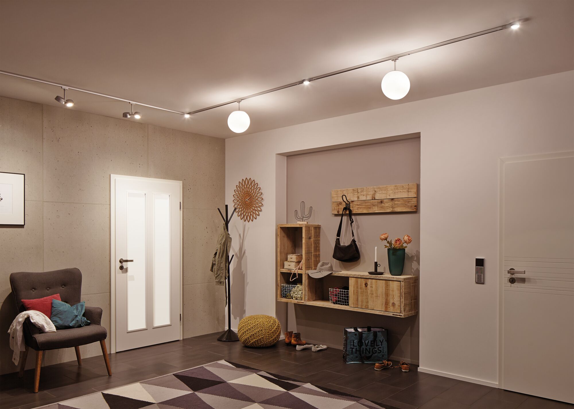 Modern hallway with white door, gray armchair, wooden shelf, and ceiling lights with LED spots and globe lamps