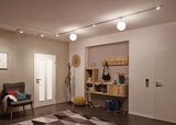 Moderner Flur mit weißer Tür, grauem Sessel, Holzregal und Deckenleuchten mit LED-Spots und Kugellampen
