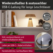 Beige Tischlampe mit austauschbarem Akku und USB-C-Ladekabel für lange Leuchtdauer im Regal.