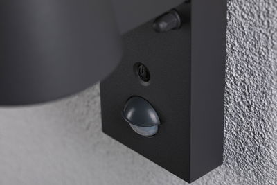 Schwarze Außenwandleuchte mit Bewegungsmelder aus Metall an grauer Wand für energiesparende Beleuchtung