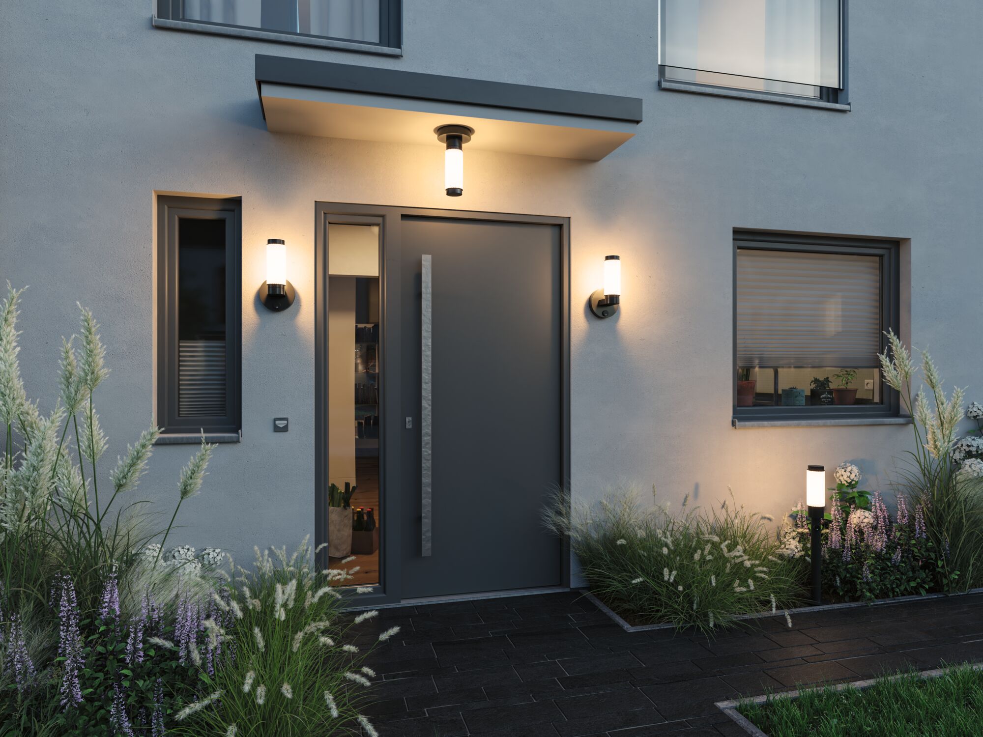 Modern black outdoor wall and ceiling lights with warm white glow at house entrance with grey door