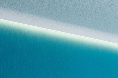 White LED strip light on ceiling with indirect lighting on blue textured wall for modern room lighting