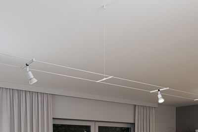 Modern white cable lighting system with two adjustable LED spotlights on ceiling for flexible lighting