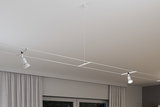 Modern white cable lighting system with two adjustable LED spotlights on ceiling for flexible lighting