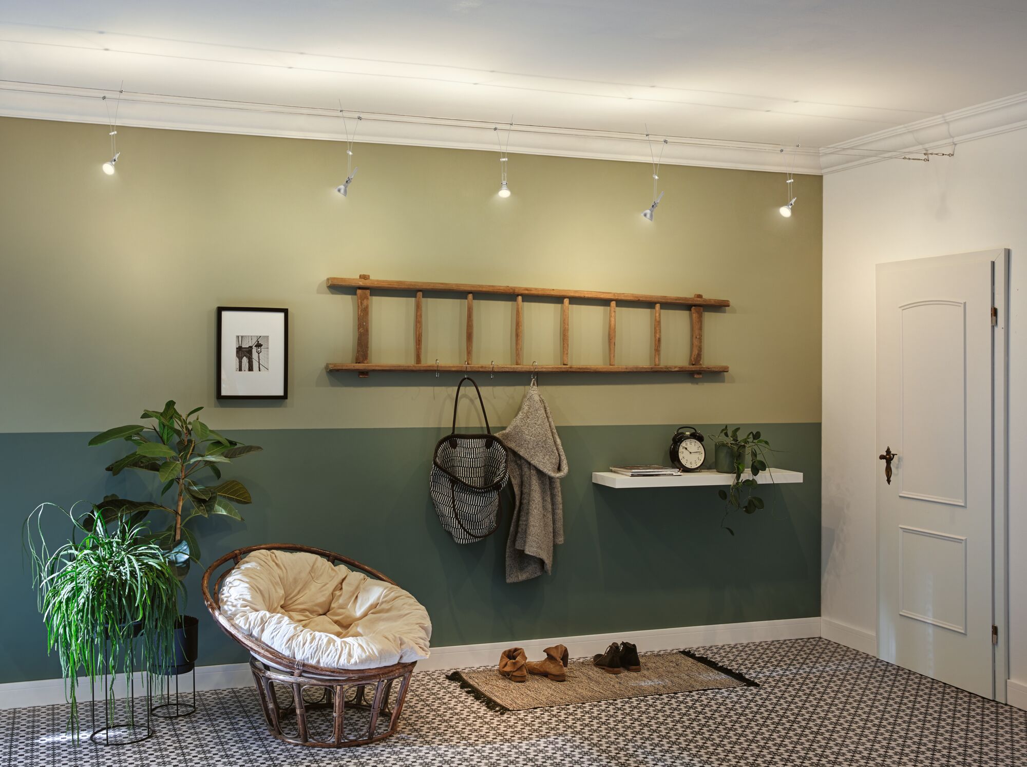 Moderne kabelhanglamp met vijf witte LED-spotjes in groene woonkamer met rotan stoel