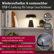 Schwarze Tischlampe mit austauschbarem Akku und USB-C-Ladekabel auf Regal mit Büchern und Deko