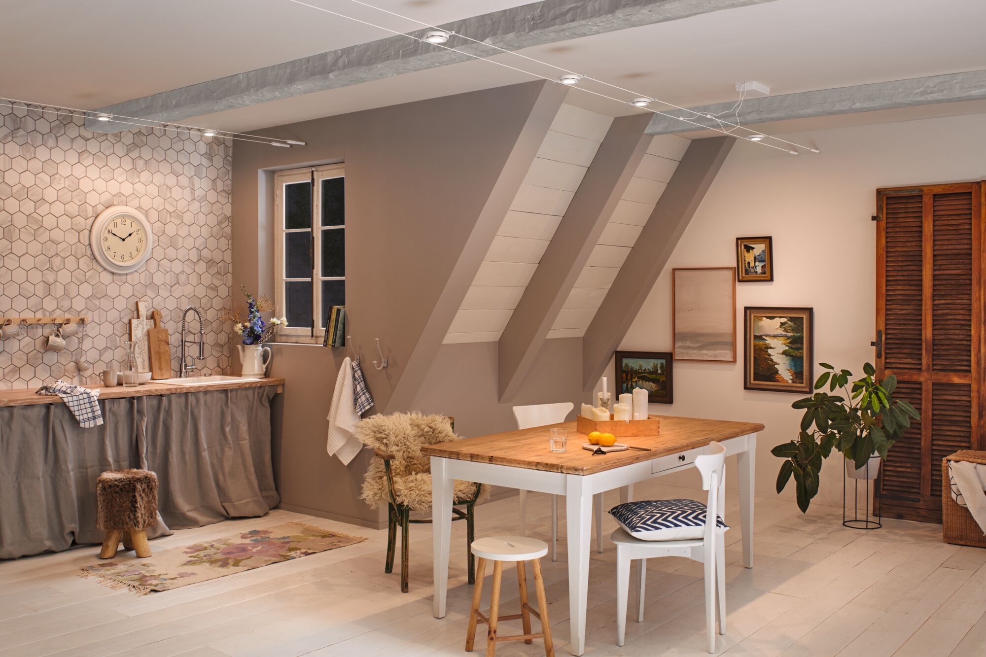 Cozy country-style kitchen with wooden table, white chairs, and modern ceiling lighting in beige and wood tones.