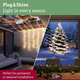 Warm white LED string lights on wooden pergola and illuminated snow-covered fir tree for seasonal outdoor lighting