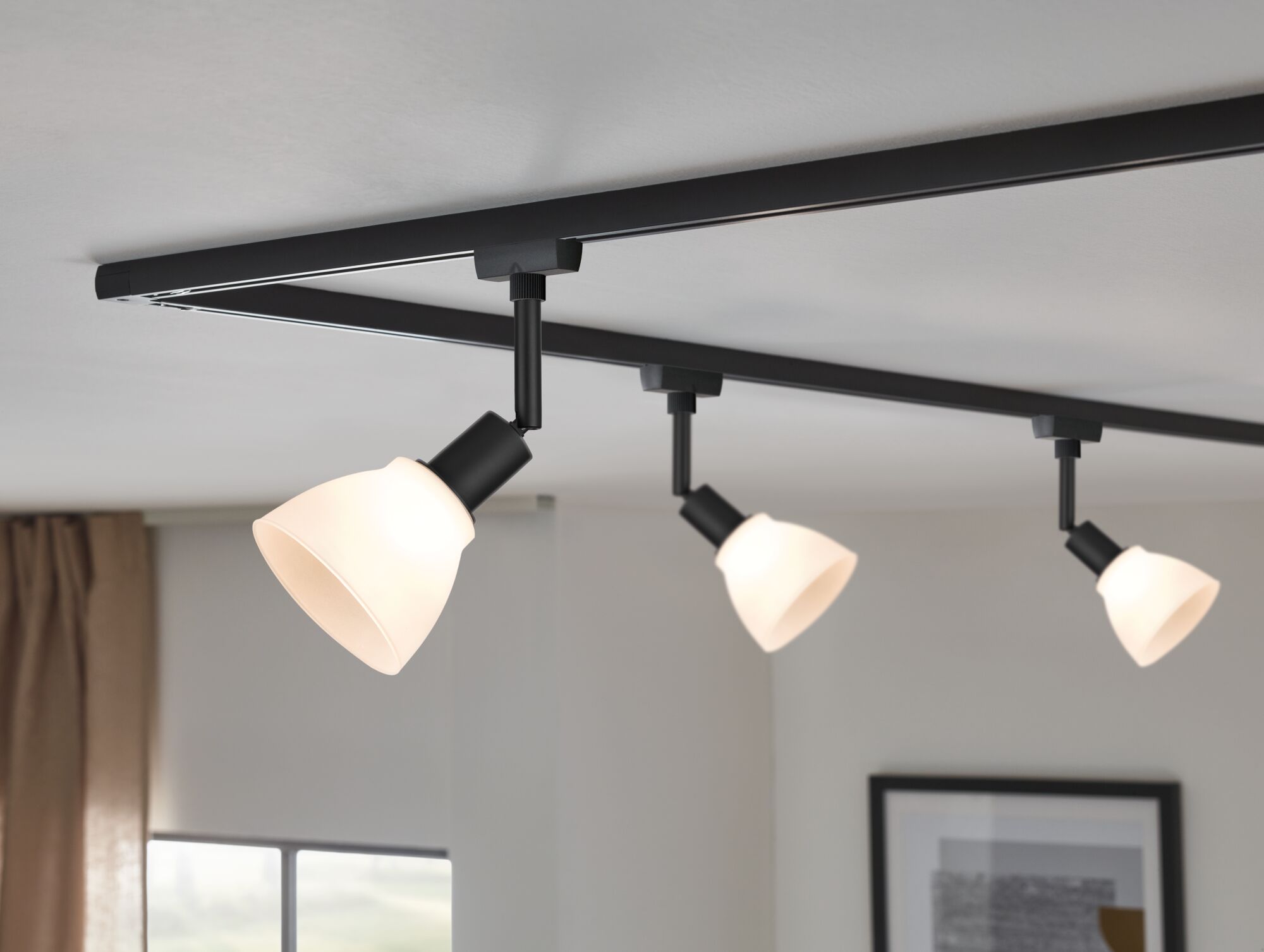 Three-light black track lighting with white glass shades for modern home illumination