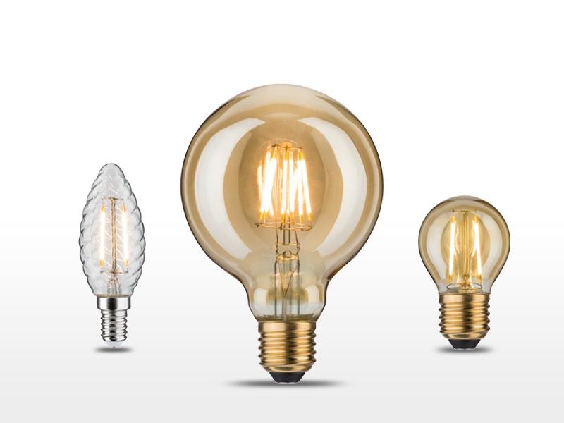 Tre dekorative vintage-pærer i forskellige former med varmt lys og gyldent glas.