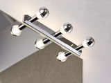 Chroomkleurige wandlamp met vier ronde lampen boven een spiegel voor badkamerverlichting
