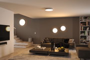 Salon moderne avec lampes LED blanches rondes au plafond et au mur, sol en bois et canapé gris