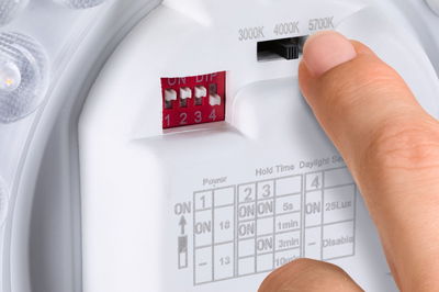 Finger stellt weißen LED-Beleuchtungsregler mit Farbtemperatur 3000K, 4000K, 5700K ein für Lichtsteuerung.