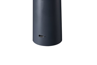 Zwart cilindrisch apparaat met USB-C-poort, modern elektronisch accessoire voor thuis.