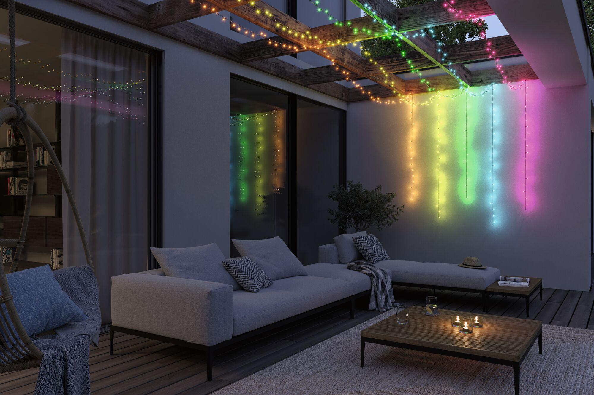 Bunte LED-Lichterketten aus Kunststoff hängen an Holzbalken über moderner Terrasse mit Sofa und Tisch.