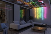 Bunte LED-Lichterketten aus Kunststoff hängen an Holzbalken über moderner Terrasse mit Sofa und Tisch.