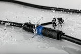 Waterdichte zwarte kabelconnector met blauwe ring, spatwaterdicht voor buitenverlichting.