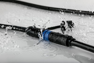 Waterproof black cable connector with blue ring, splash-proof for outdoor lighting applications.