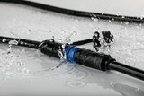 Waterproof black cable connector with blue ring, splash-proof for outdoor lighting applications.