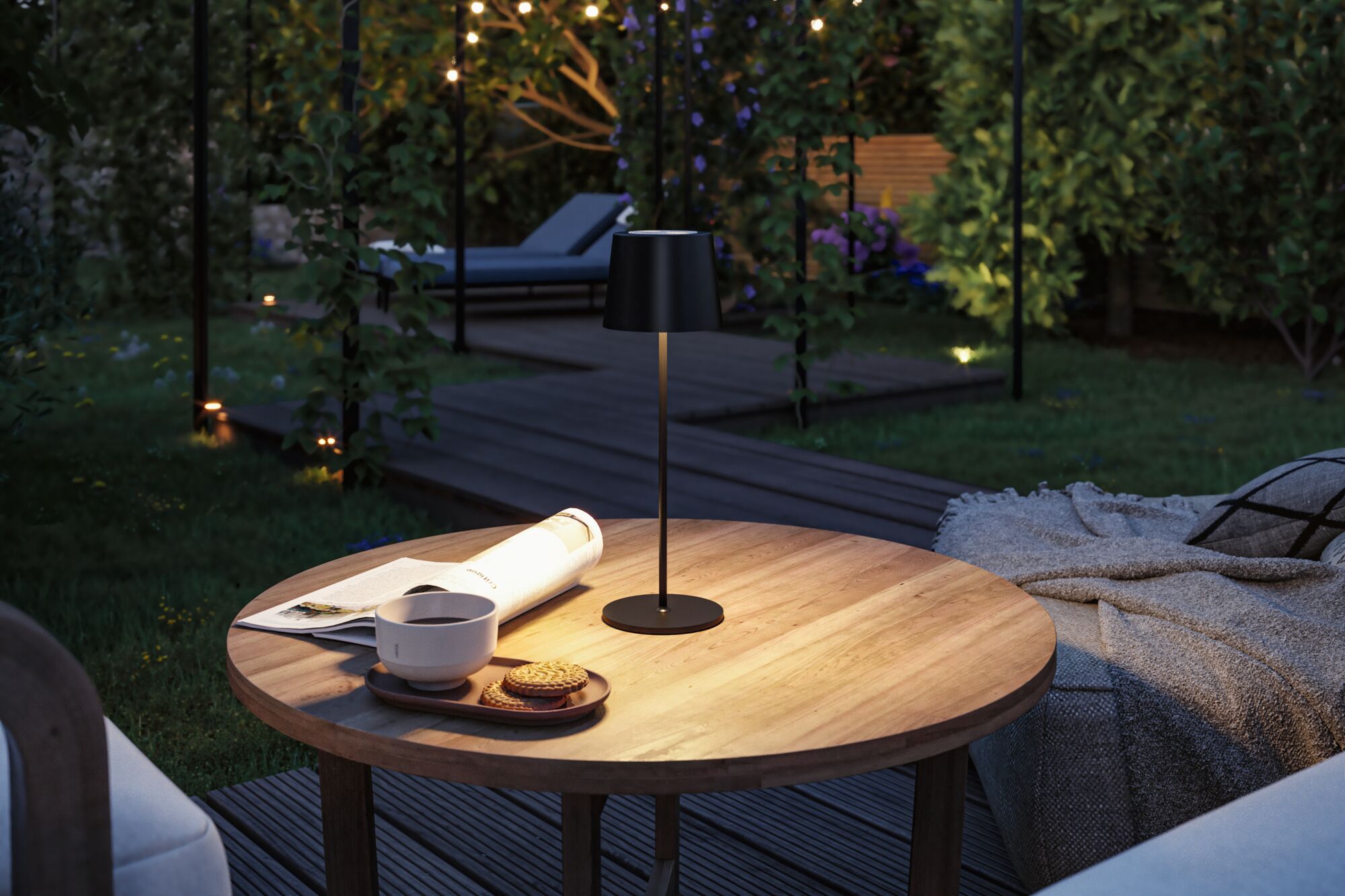 Black metal LED table lamp on wooden garden table with newspaper and coffee cup.