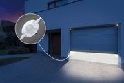 Weißer LED-Bewegungsmelder aus Kunststoff für Außenbeleuchtung an moderner Garage bei Nacht