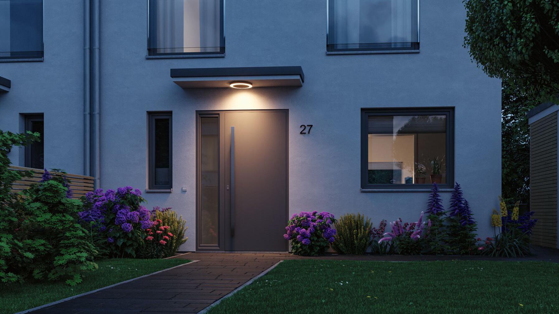Moderne Außenbeleuchtung mit rundem LED-Wandlicht in Schwarz über Haustür und Gartenweg bei Abenddämmerung
