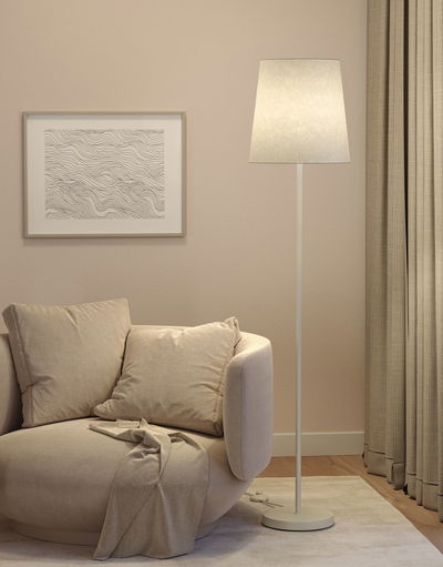 Beige floor lamp with fabric shade beside round sofa and abstract wall art in living room