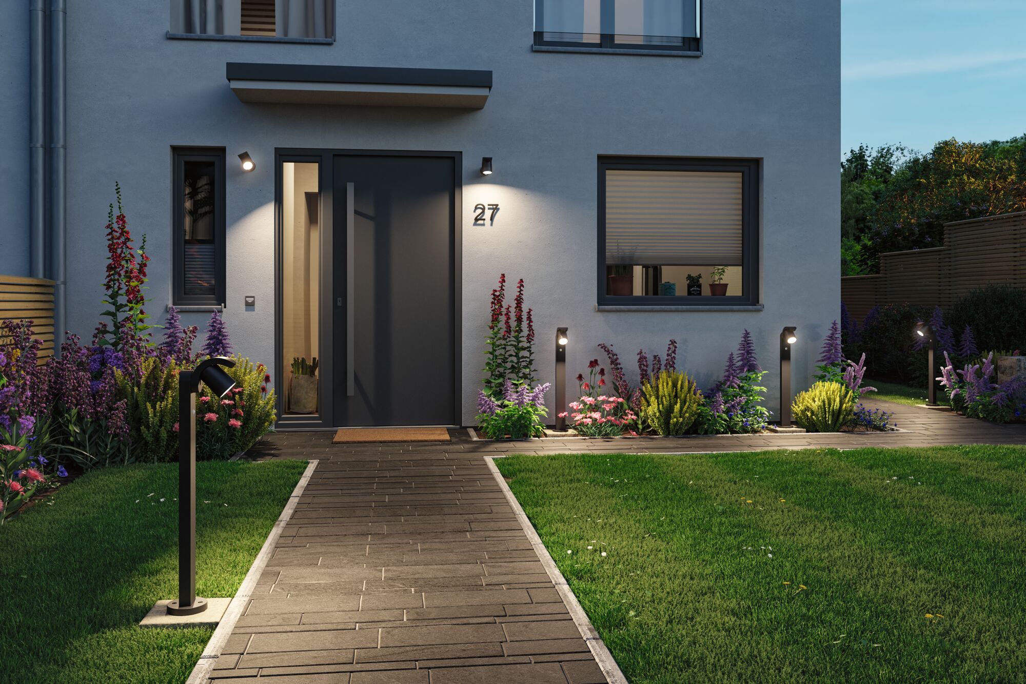 Modern entrance with black outdoor lights and well-kept garden featuring colorful flowers.