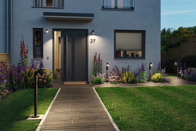 Moderner Eingangsbereich mit schwarzer Außenbeleuchtung und gepflegtem Garten mit bunten Blumen.