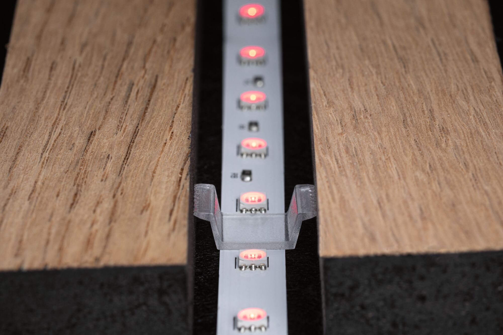 LED-Lichtleiste mit roten LEDs in Aluminiumprofil zwischen zwei Holzplatten für indirekte Beleuchtung