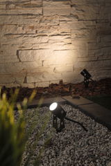 Black LED outdoor spotlight on gravel with warm white light, perfect for garden and wall lighting