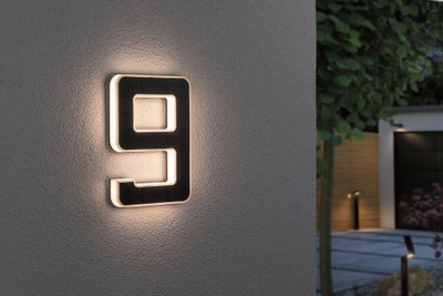 Lumière de numéro de maison noire moderne avec bord LED blanc chaud sur mur gris pour éclairage extérieur
