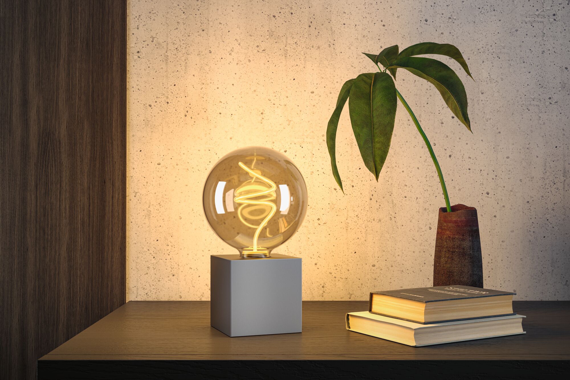 Moderne Tischlampe mit warmweißem LED-Glühfaden in transparentem Glaskugel auf grauem Würfel.