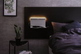 Modern bedroom with black headboard and white LED wall light featuring shelf and USB port
