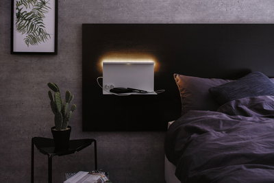 Modern bedroom with black headboard and white LED wall light featuring shelf and USB port