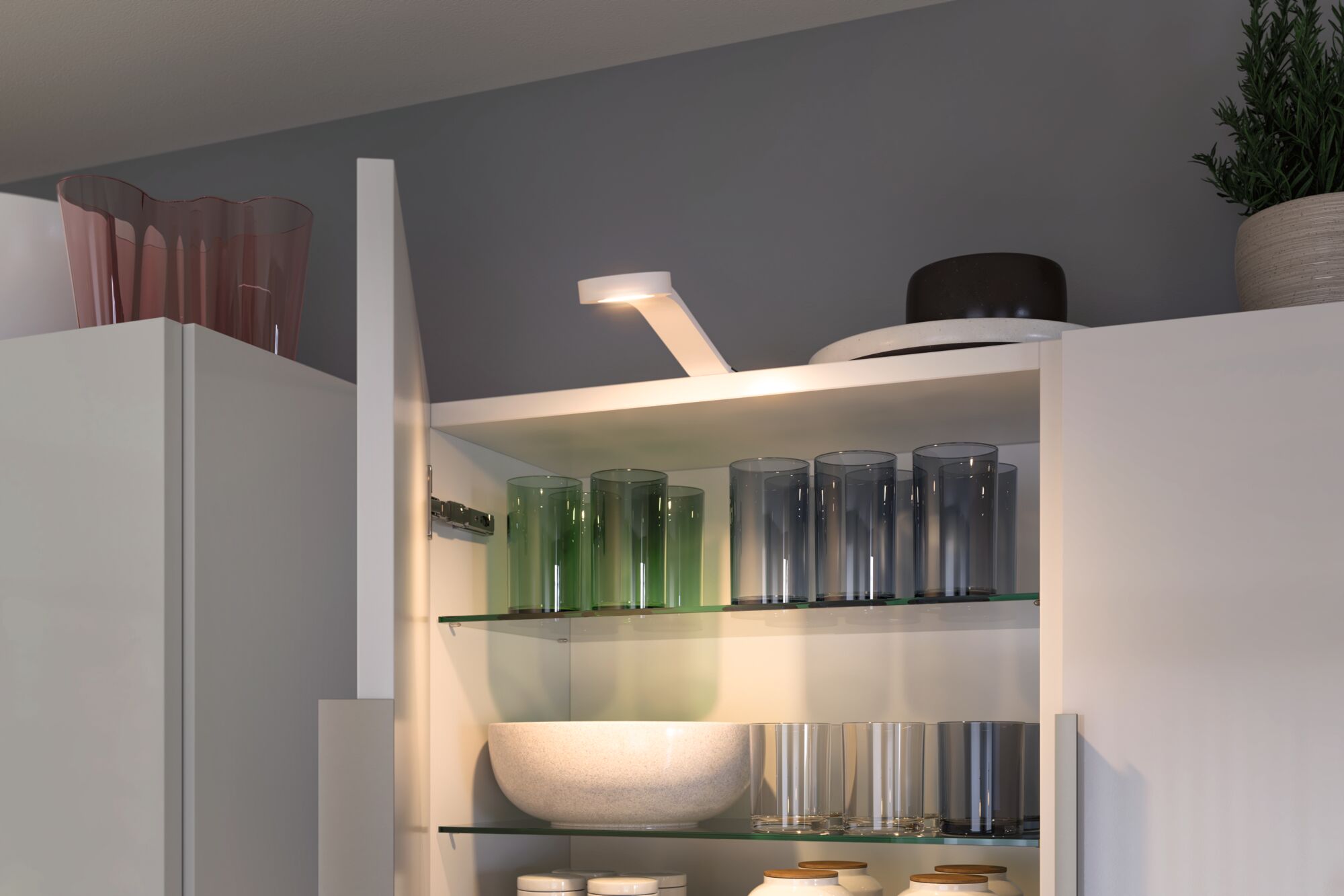 White LED cabinet spotlight illuminating glasses and bowls on glass shelves in modern kitchen cabinet