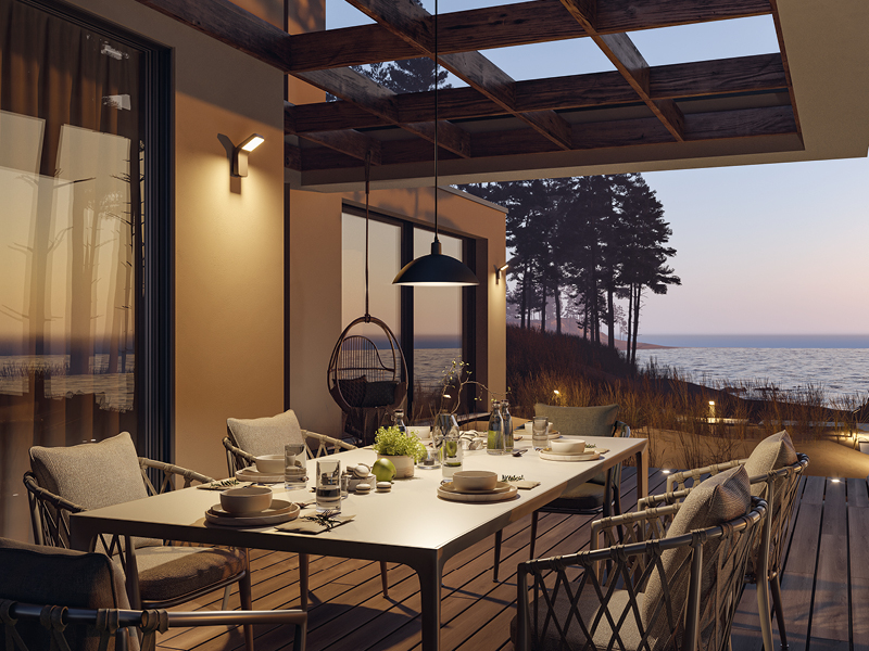 Espace repas extérieur moderne avec table éclairée et luminaires résistants à l'eau de mer au coucher du soleil