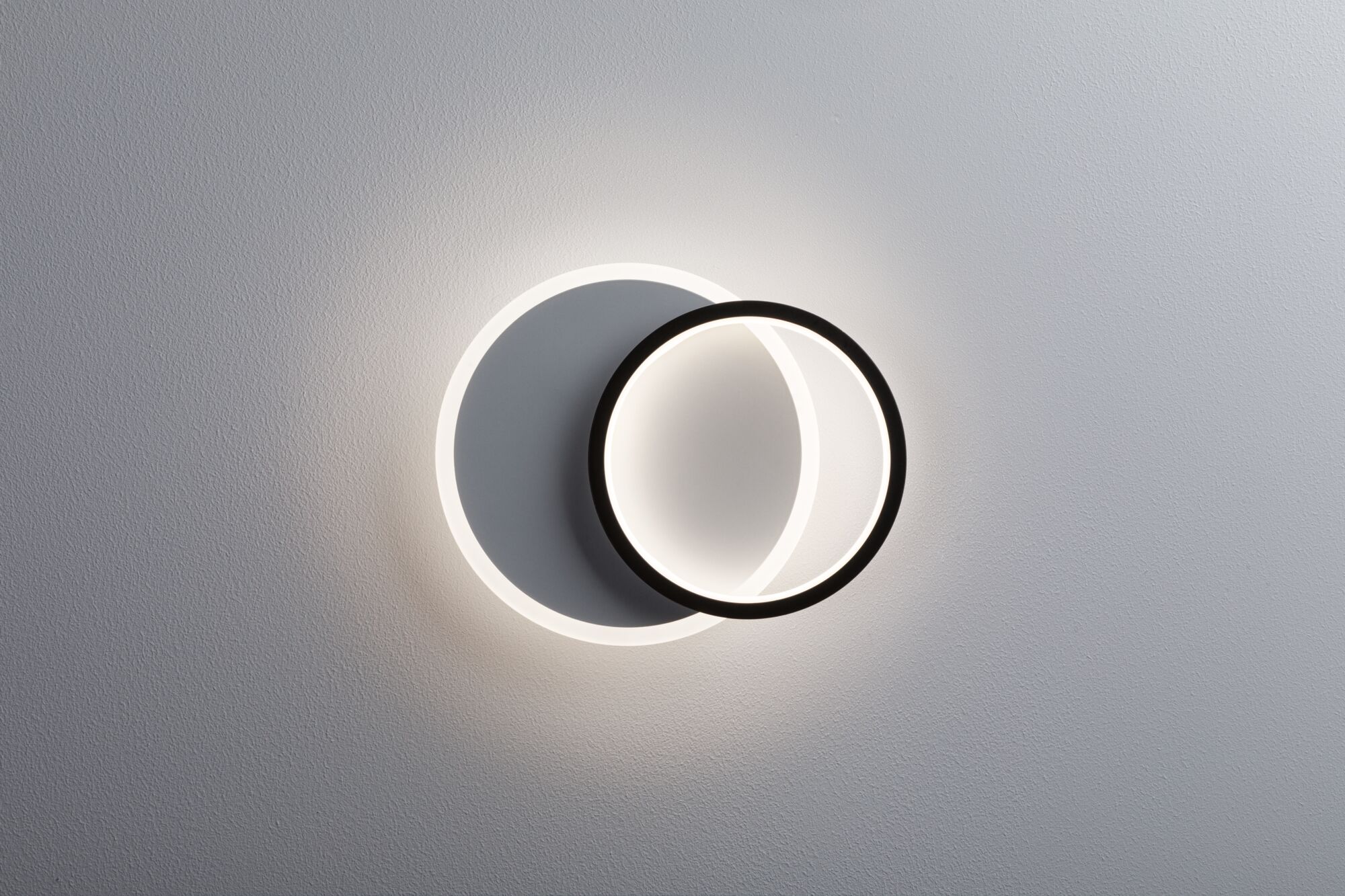 Modern LED wall light with two overlapping black and white rings for stylish room lighting