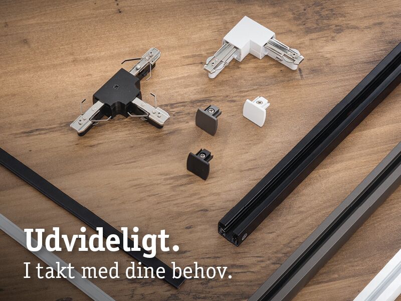 Modulære sorte og hvide metal- og plastikskinneforbindelser på træoverflade til LED-skinnebelysning