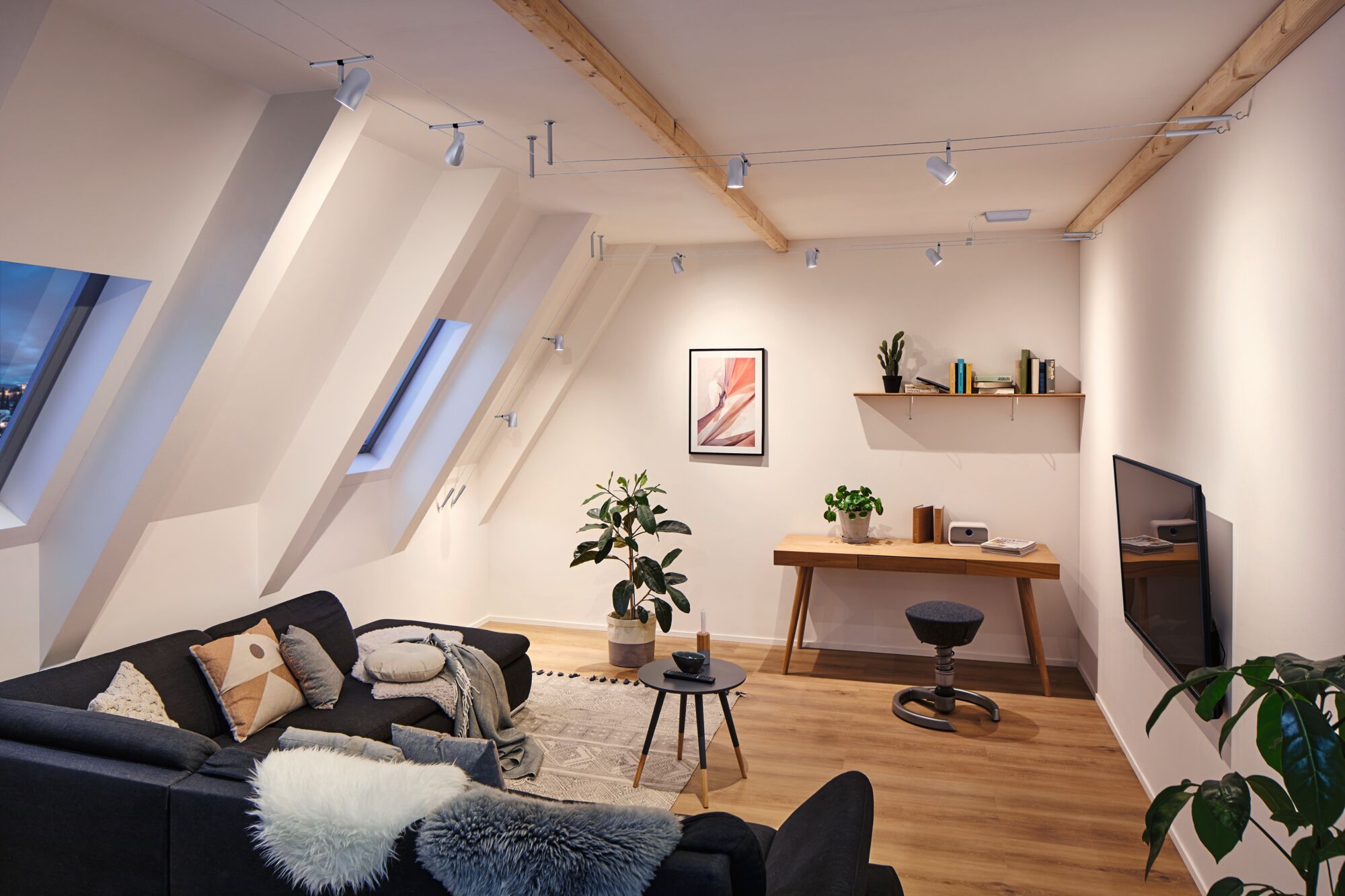 Modernes Wohnzimmer mit grauem Sofa, Holztisch und weißem Seil-Lichtsystem an der Decke