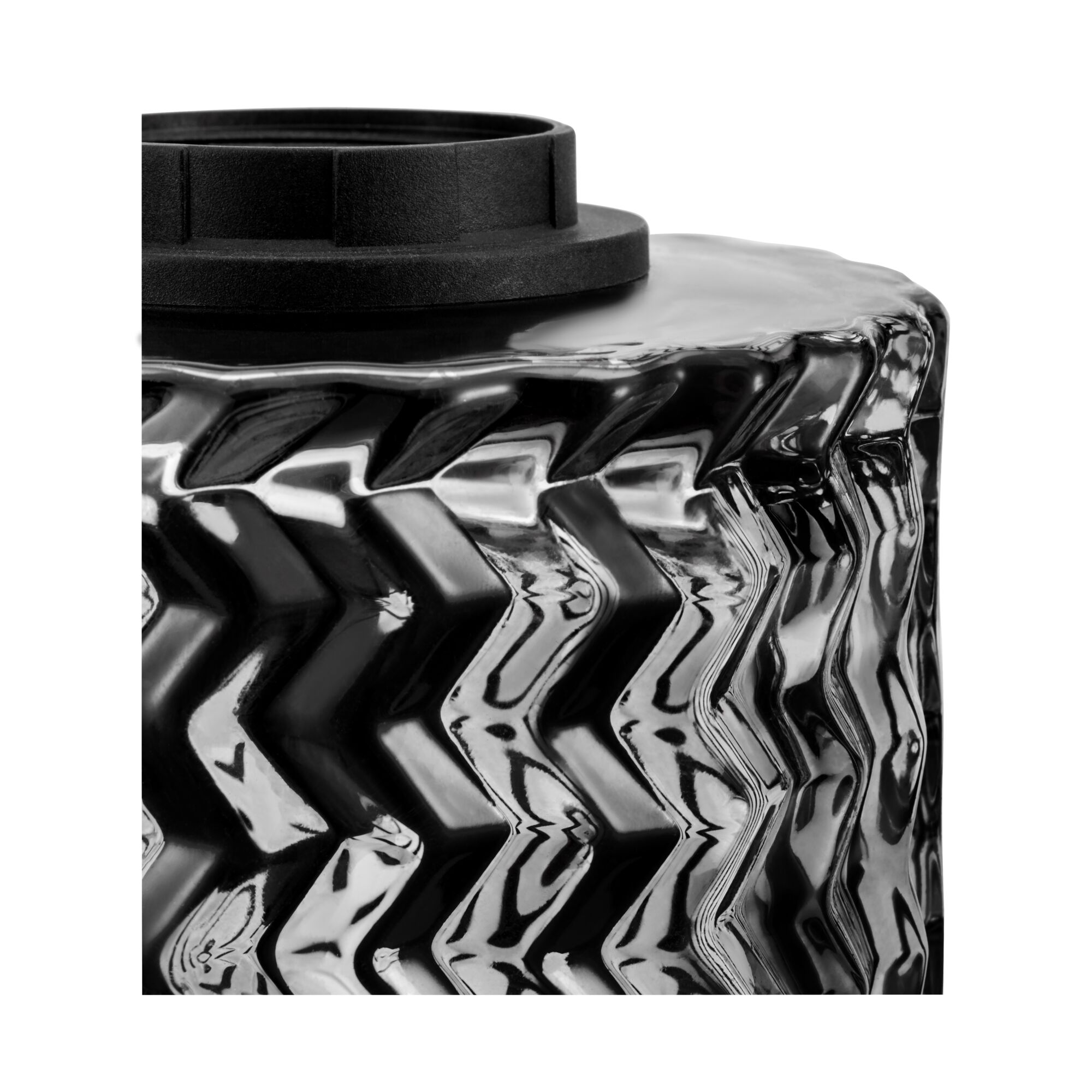 Close-up of black plastic lid on textured glass surface with zigzag pattern