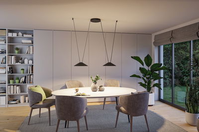 Modern dining area with white oval table, grey chairs, and black metal pendant lights