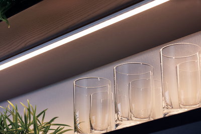White LED under-cabinet light with warm white glow above clear glasses on shelf