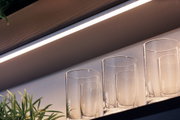 White LED under-cabinet light with warm white glow above clear glasses on shelf