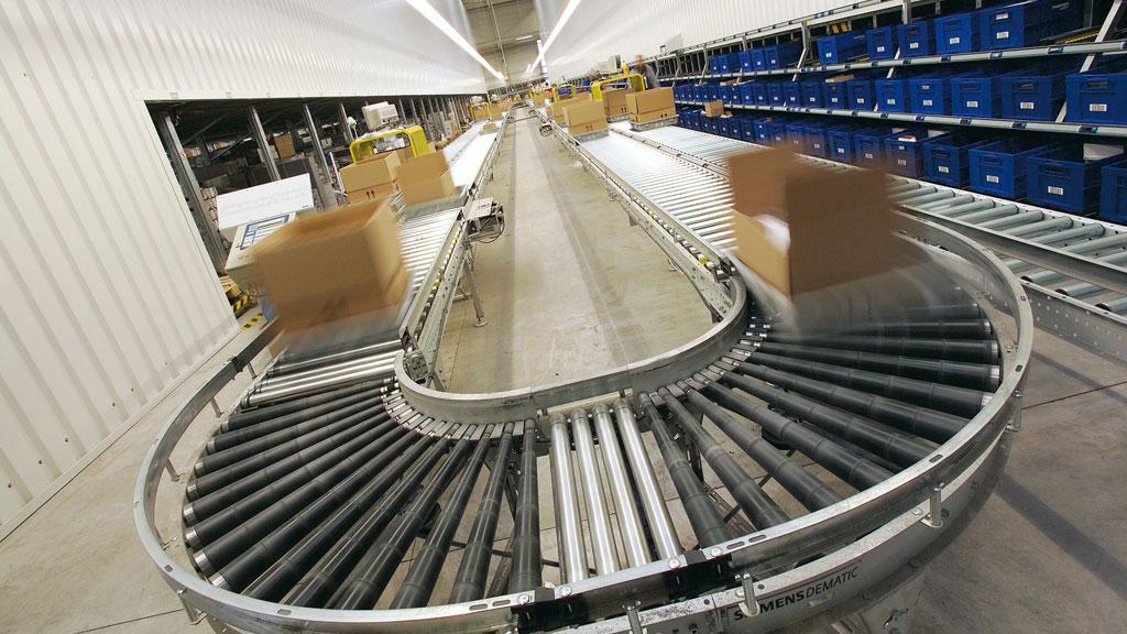 Logistikzentrum mit Förderband aus Metall und Kartons in Bewegung für effiziente Warenverteilung