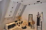 Modern room with black cable-pulled ceiling light, mirror, wicker chair, and warm decorative accents