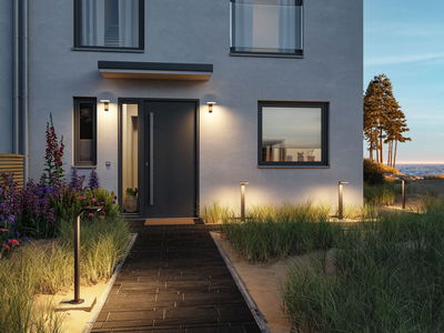 Modern outdoor lighting with black LED path lights and wall lamps on grey house with garden path.